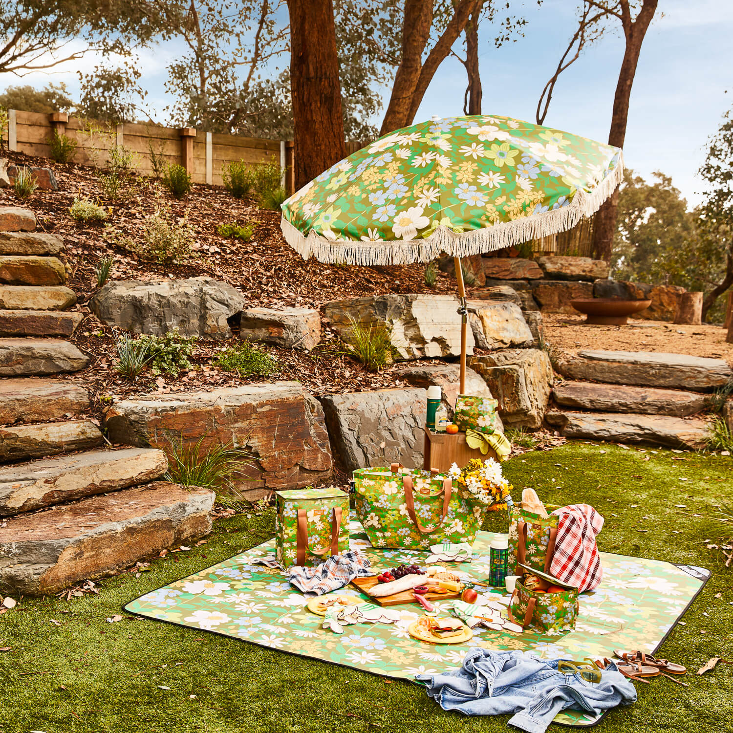 rocky-landscape-design-green-lawn-picnic-setup-umbrella-rug-food